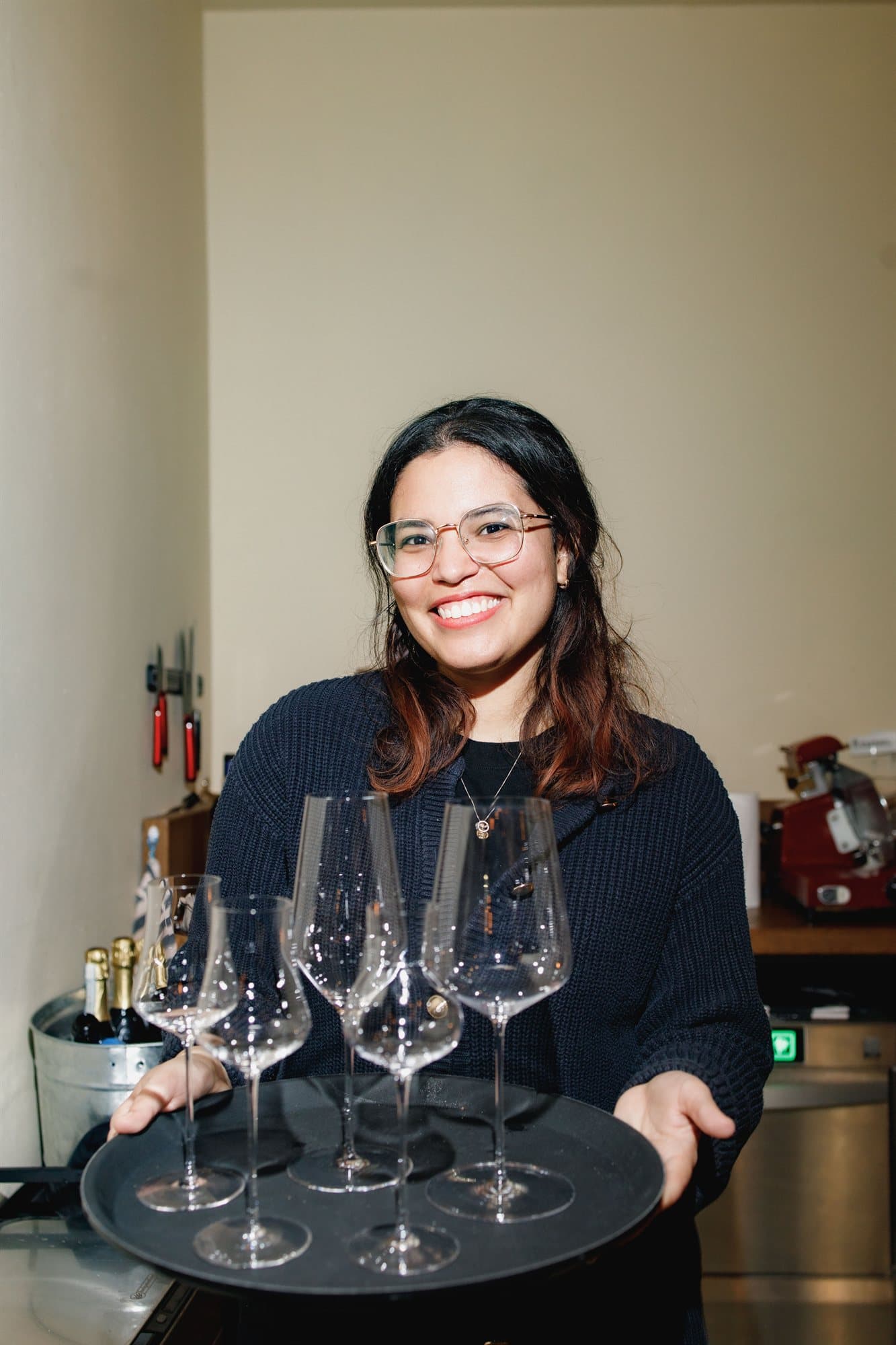 A smiling member of the Cin Cin team carrying a tray of wine glasses