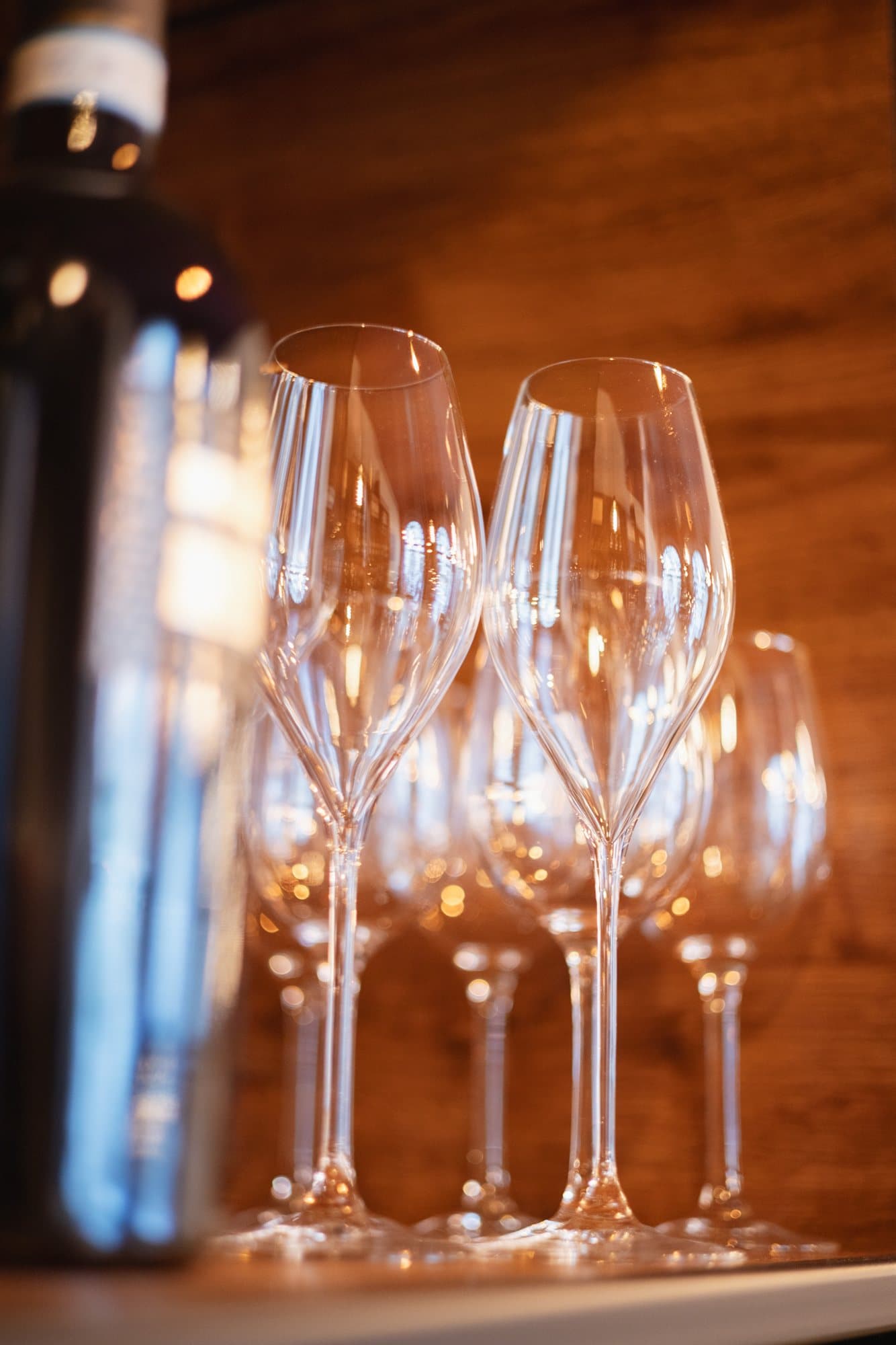 Wine glasses lined up beside a bottle in warm candlelight